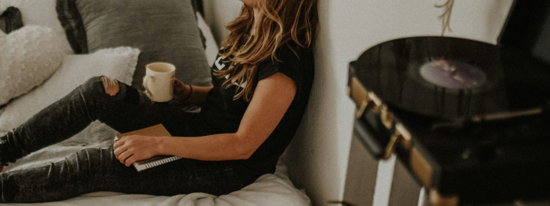 woman leaning on wall while sitting on bed